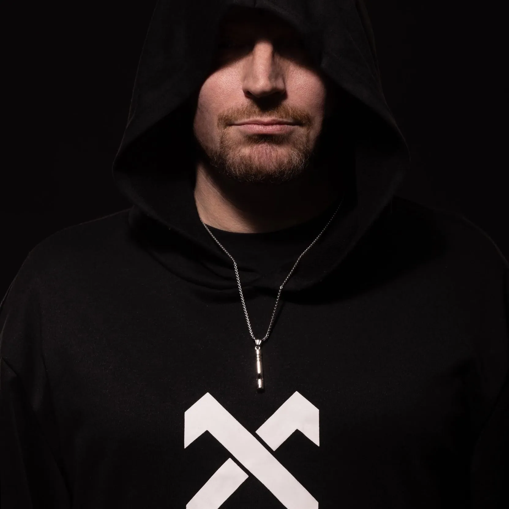 NICHOLSON in a black hood against a dark studio background
